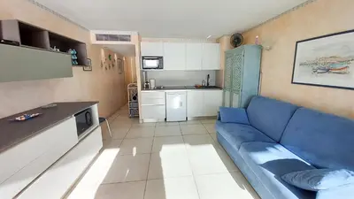 a living room with a blue couch and a kitchen at Les terrasses in Cannes