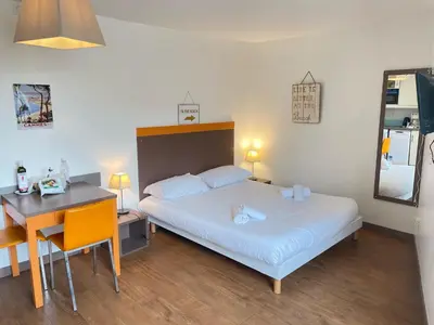 a bedroom with a bed and a table and a desk at Studio Piscine & Parking by Connexion in Cannes