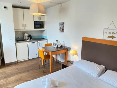 a room with a bed and a table and a kitchen at Studio Piscine & Parking by Connexion in Cannes