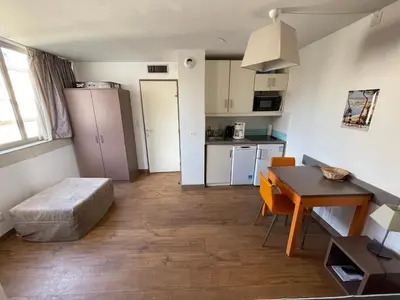 a small apartment with a table and a kitchen at Studio Piscine & Parking by Connexion in Cannes