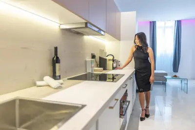 a woman in a black dress standing in a kitchen at Residence Meynadier - apartments - New - AC - Wifi - Close Beach and Palais - LRA Cannes in Cannes