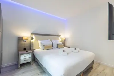 a bedroom with a large white bed and a night stand at Residence Meynadier - apartments - New - AC - Wifi - Close Beach and Palais - LRA Cannes in Cannes