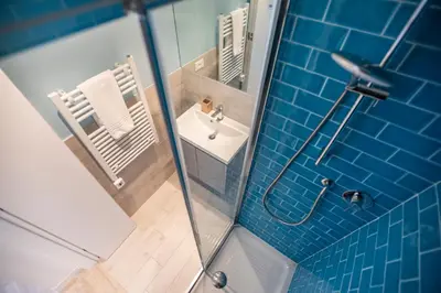 a bathroom with a sink and a shower with blue tiles at La Casa Blu by Connexion in Cannes