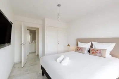 a white bedroom with a large white bed with pillows at Superbe appartement à Cannes vue mer panoramique 