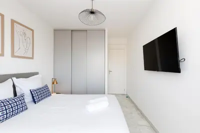 a white bedroom with a bed and a flat screen tv at Superbe appartement à Cannes vue mer panoramique 