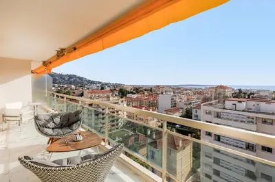 a balcony with two chairs and a table on a building at Superbe appartement à Cannes vue mer panoramique 