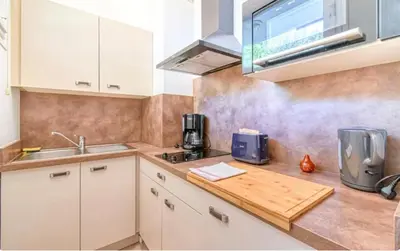 a kitchen with white cabinets and a wooden counter top at Le Capri - Studio Wifi Californie in Cannes
