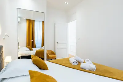 a bedroom with two beds and a mirror at 3-Br Apartment in the heart of downtown in Cannes