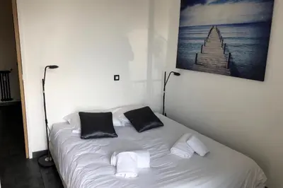 a white bed with two black pillows on it at Cosy 42m With Balcony Nice View And Wifi in Cannes