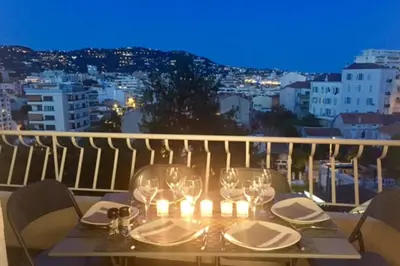 a table with wine glasses and candles on a balcony at Cosy 42m With Balcony Nice View And Wifi in Cannes
