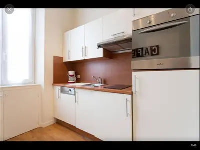 a kitchen with white cabinets and a stainless steel refrigerator at 2 pièces cannes centre in Cannes