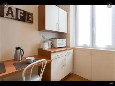 a kitchen with white cabinets and a table with a microwave at 2 pièces cannes centre in Cannes