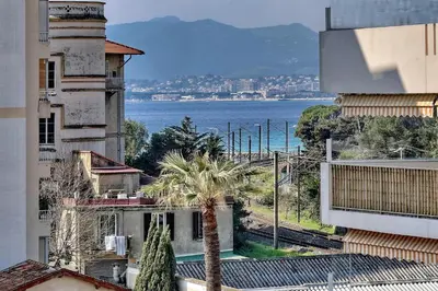 a view of the ocean from a building with a palm tree at Agréable 2 pièces TERRASSE, PISCINE, Clémenceau A1B235 in Cannes