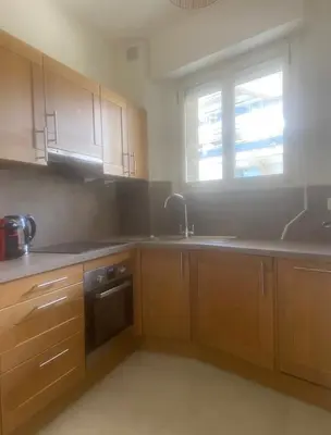 a kitchen with wooden cabinets and a sink and a window at palm Beach studio vue port Canto in Cannes
