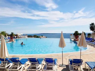 a man swimming in a swimming pool with chairs and umbrellas at Apartment Villa Francia-2 by Interhome in Cannes