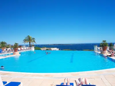 a large swimming pool with people laying in chairs in a resort at Apartment Villa Francia-2 by Interhome in Cannes
