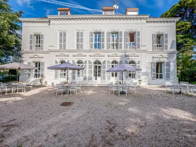 a large white house with tables and umbrellas at Apartment Villa Francia-2 by Interhome in Cannes