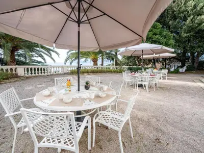 a group of tables and chairs with an umbrella at Apartment Villa Francia-2 by Interhome in Cannes