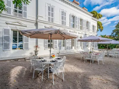a table and chairs with umbrellas in front of a building at Apartment Villa Francia-2 by Interhome in Cannes