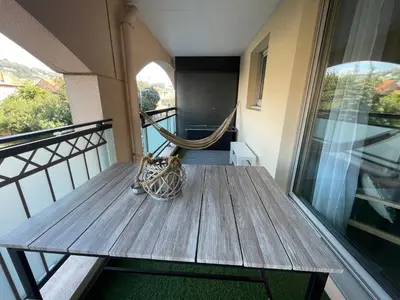 a wooden table on a balcony with a hammock at CHEZ MATHIEU in Cannes