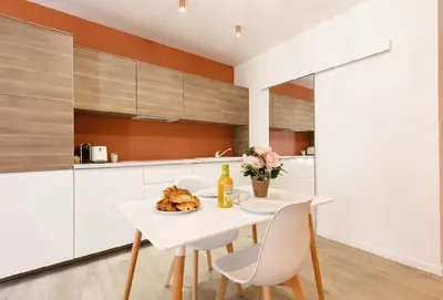 a white kitchen with a white table and chairs at Studio O - ascenseur - 2 min du Palais - Climatisé in Cannes