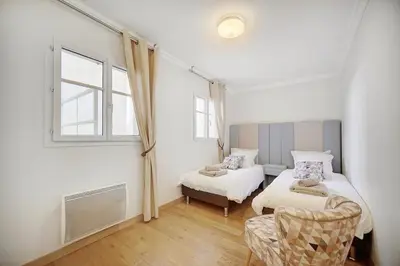 a bedroom with two beds and a chair and a window at Cannes banane 50m croisette, luxueux 4 pièces dans résidence de standing in Cannes