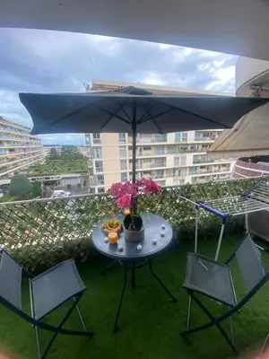 a table and two chairs and an umbrella on a balcony at Appart 1 pièce pointe de la Croisette à cannes in Cannes