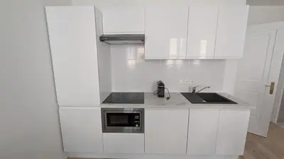 a white kitchen with a sink and a microwave at La Fontaine in Cannes