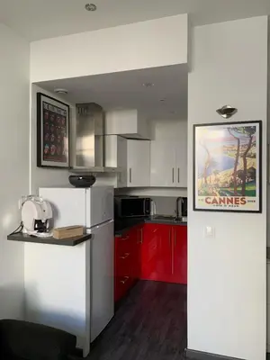 a kitchen with red cabinets and a white refrigerator at Appartement 2 pièces centre ville Cannes in Cannes