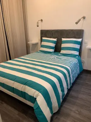a bed with blue and white striped sheets and pillows at Appartement 2 pièces centre ville Cannes in Cannes