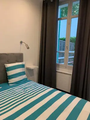 a bed with a striped pillow and a window at Appartement 2 pièces centre ville Cannes in Cannes