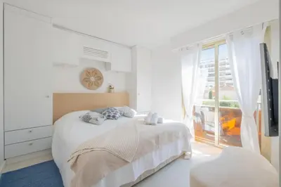 a white bedroom with a bed and a window at Stylish 2-Br Apartment Steps from the Croisette in Cannes