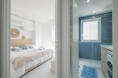 a white bedroom with a bed and a bathroom at Stylish 2-Br Apartment Steps from the Croisette in Cannes