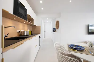a white kitchen with a sink and a counter at Stylish 2-Br Apartment Steps from the Croisette in Cannes