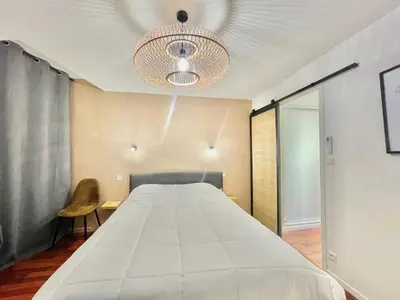 a bedroom with a large white bed and a chandelier at Carré d'or Duplex, by Welcome to Cannes in Cannes
