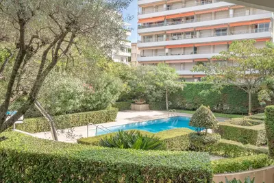 a garden with a swimming pool and a tall building at Le Parisien by Winsome Destination in Cannes