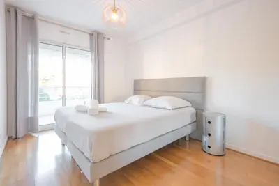 a white bedroom with a large bed and a window at Le Parisien by Winsome Destination in Cannes