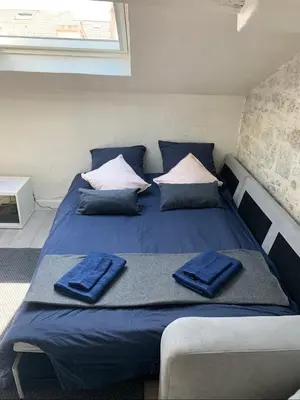 a bed in a room with blue sheets and pillows at Mansarde Cannes in Cannes