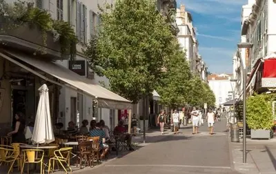 people walking down a city street with tables and chairs at Mansarde Cannes in Cannes