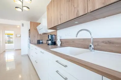 a kitchen with a white sink and wooden cabinets at 3-Br apartment near downtown Cannes Sea view parking in Cannes