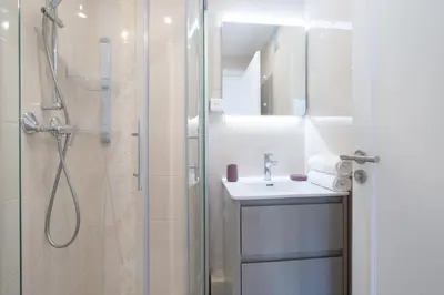 a white bathroom with a shower and a sink at 3-Br apartment near downtown Cannes Sea view parking in Cannes