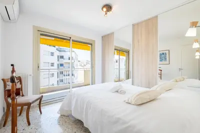 a white bedroom with a large bed and a window at 3-Br apartment near downtown Cannes Sea view parking in Cannes