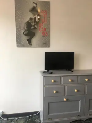 a bedroom with a dresser with a tv and a picture on the wall at Cannes center terrace AC Wifi 200 m from sea behind Martinez in Cannes
