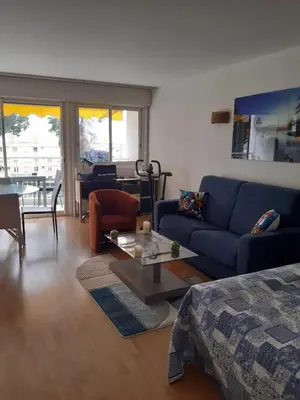 a living room with a blue couch and a table at SPACIEUX STUDIO 37m2 - Terrasse VUE MER in Cannes
