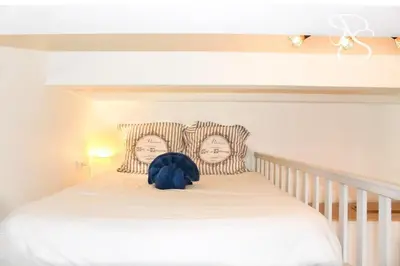 a white bed with a headboard with two people on it at Beautiful studio Cannes Center in Cannes
