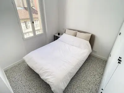 a white bed in a small room with a window at 2 bedroom Majestic, 1 min to the Croisette 357 in Cannes