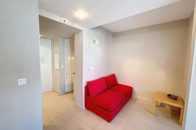 a red chair in a room with a table at HENRI CAMILLE REAL ESTATE - Rouaze 2 -Studio à 50m center in Cannes
