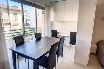 a dining room with a wooden table and chairs at HENRI CAMILLE REAL ESTATE - Rouaze 2 -Studio à 50m center in Cannes