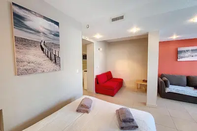 a living room with a bed and a red chair at HENRI CAMILLE REAL ESTATE - Rouaze 2 -Studio à 50m center in Cannes