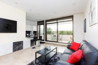 a living room with a black leather couch and red pillows at Gray d'Albion 1D2 YourHostHelper in Cannes